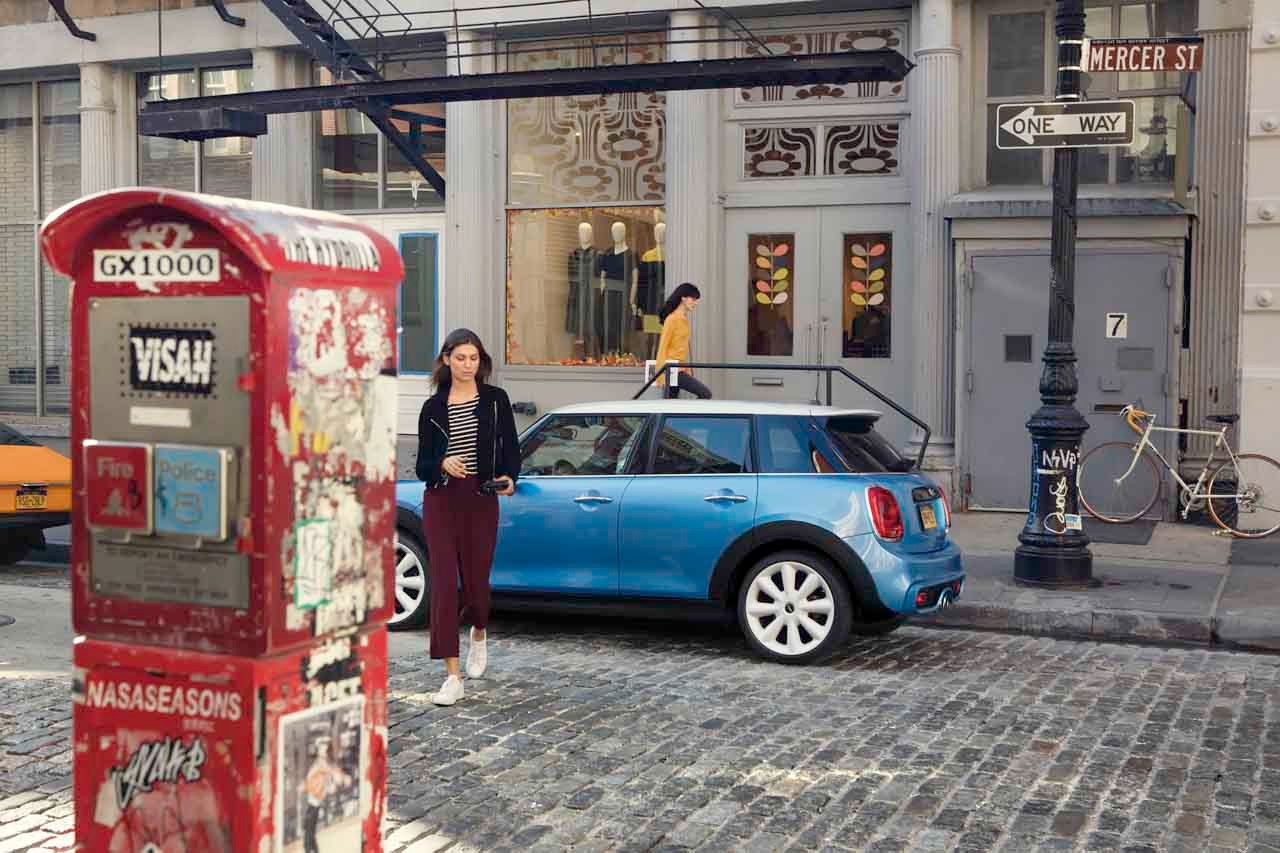 Perspectivă din lateral-stânga a unui MINI albastru staţionând într-un peisaj urban